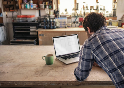 Craftsman working online with a laptop in his workshop - Powered by Adobe