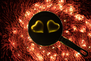 A warm color light garland surrounding two hearts inside pan. valentine's day.
