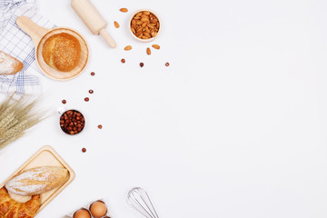 Homemade breads or bun, croissant and bakery ingredients, flour, almond nuts, hazelnuts, eggs on white background, Bakery background frame, Cooking breakfast concept. Flat lay, Top view and copy space