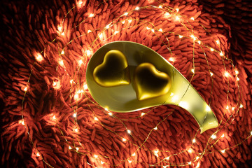 A warm color light garland surrounding two hearts inside plate. valentine's day.