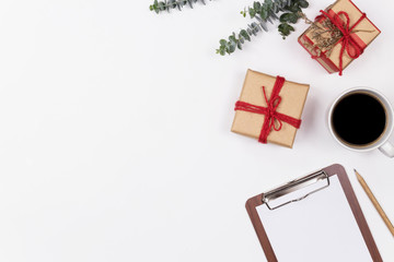 Workspace empty clipboard with eucalyptus and gift box on white background. Flat lay, top view. Image.