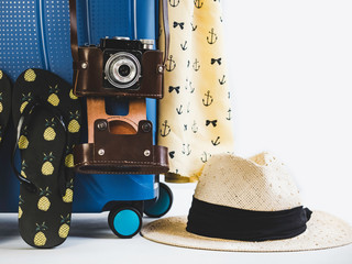 Stylish suitcase, vintage camera and sun hat on white isolated background. Close-up. Preparing for the summer trip