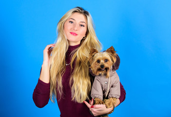 Dressing dog for cold weather. Which dog breeds should wear coats. Woman carry yorkshire terrier. Dogs need clothes. Girl adorable blonde hug little dog in coat. Apparel and accessories. Pet supplies