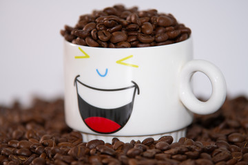 white cup with a pattern and coffee beans