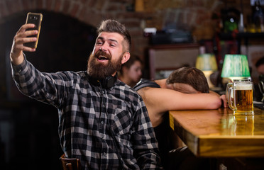 Taking selfie concept. Online communication. Send selfie to friends social networks. Man in bar drinking beer. Take selfie photo to remember great evening in pub. Man bearded hipster hold smartphone