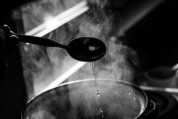 the man stirs the soup in the pan from which steam comes