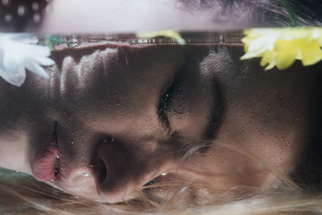 close up of young girl posing underwater with flowers
