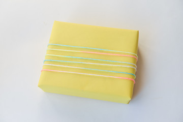 yellow gift box on a white background. winter holidays, pompom from threads, warm. unusual