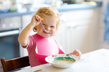 Adorable baby girl eating from spoon vegetable noodle soup. food, child, feeding and development...