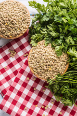 Uncooked lentils in wooden bowles  with parsley herbs on kitchen table