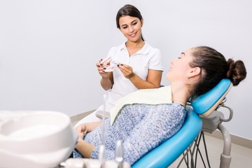 Dentist girl consults the patient in the clinic showing the layout of the jaw