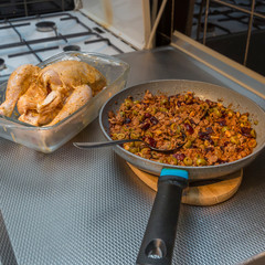 Fresh and raw whole chicken spread with butter and next to a pan with ground beef prepared with olives, raisins, walnuts. Homemade traditional food concept