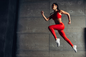 Fototapeta na wymiar Young fit woman jumping while running Fitness sport girl exercising.