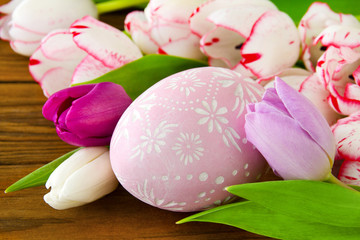 Easter egg decoration and tulips against wooden background