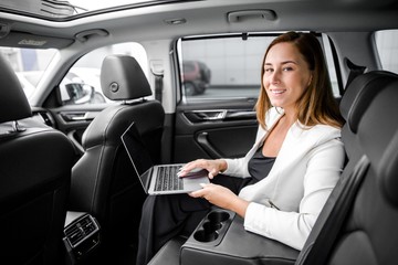 Fototapeta na wymiar Business woman sitting in the back seat of a car working at a laptop