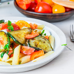 Closeup margarita pasta, warm penne salad with tomatoes, zucchini, mozzarella and basil.