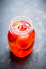 Red cocktail with cherry and lime in jar on the rustic background. Selective focus. Shallow depth of field.