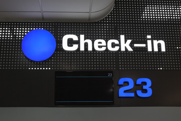Check in desk at international airport, checkin counter and monitor for flight information display, blue round sign close up, layout for passenger air transportation and flight ticket registration