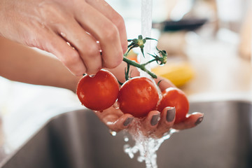 Woman washing tomatoes in kitchen sink close up.