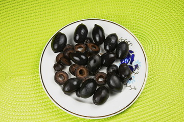 black olives on a  porcelain plate on green  background