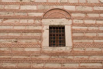 Byzantine brickwork, the wall of an old building with a window and forged metal lattices. Istanbul, Turkey