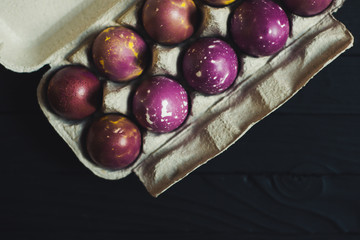 dyed easter eggs in box at black wooden background