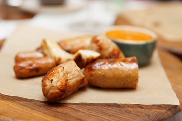Cut sausages fried on grill, served on wooden board
