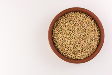 Natural fresh green buckwheat in clay bowl isolated on white background.