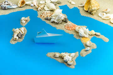 Paper ship worth saving Italy. Map of Italy and the islands are laid out of sand and shells.
