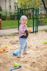 Baby girl playing in the sandbox on the Playground.