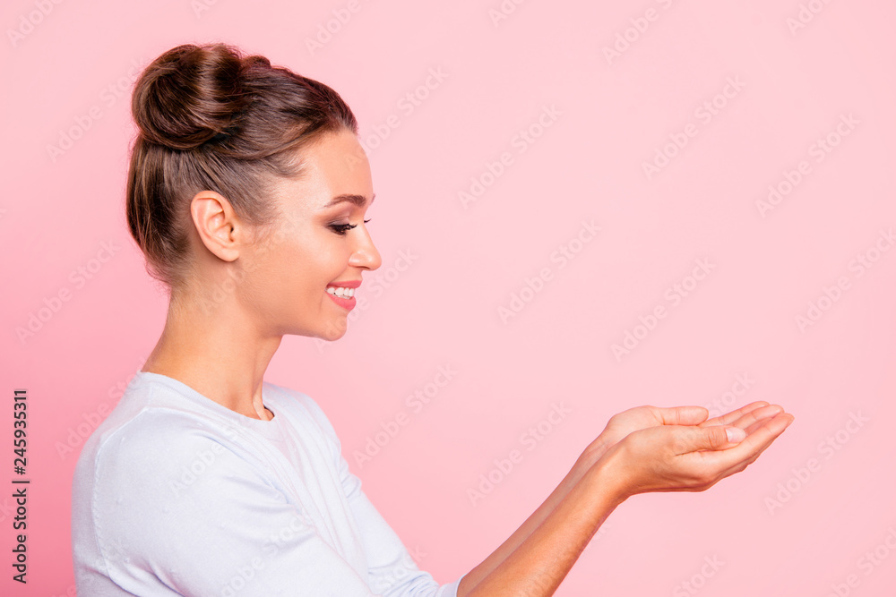 Wall mural Profile side view portrait of her she nice cute adorable fascinating attractive lovely sweet cheerful girl lady holding object on palms isolated over pastel pink background