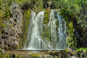 Fototapeta na wymiar Waterfall flowing down a green moss covered rock wall