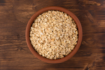 Rolled oats or oat flakes in bowl on wooden background. Healthy lifestyle, healthy eating concept. Top view