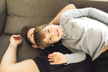A father playing on the couch at home with his son