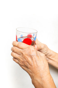 Senior woman's hand holding polka dot grass,  drinking water on white background