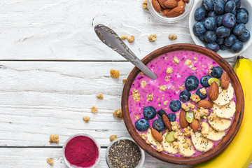 Obraz na płótnie Canvas Acai smoothie bowl topped with banana, chia and pumpkin seed, blueberry, almonds and granola with spoon