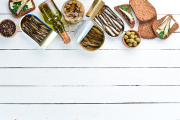 Sprats with oil in a jar. On a white wooden background. top view. Free copy space.