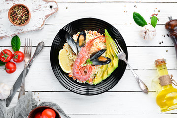 Couscous with avocados and seafood. Shrimp and mussels. On the old background. Top view. Free space for your text.