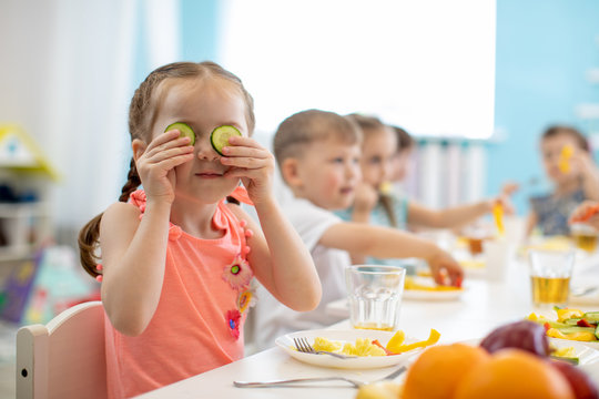 Funny kid eating healthy food in kindergarten or daycare