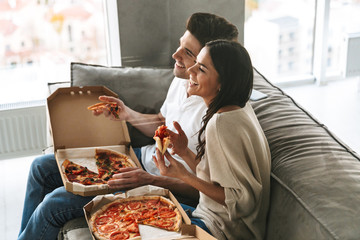 Cheerful young couple sitting on a couch at home