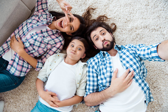 Self-portrait top above high angle view of nice cute charming attractive cheerful cheery foolish dumb people mom dad lying on floor carpet showing v-sign in light white modern interior indoors
