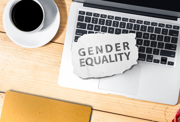 Laptop and paper with gender equality text on wooden table