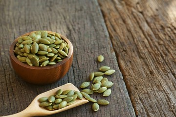 Pumpkin grain in wooden bowl on classic wooden table background, cereal