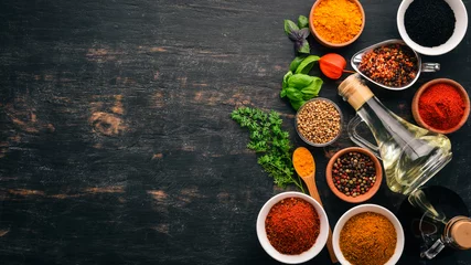 Foto op Plexiglas A set of spices and herbs. Indian cuisine. Pepper, salt, paprika, basil, turmeric. On a black wooden chalkboard. Top view. Free copy space. © Yaruniv-Studio