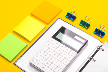 calculator on Notepad and stickers next isolated on yellow background