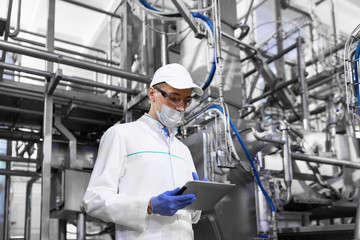 man in a mask and a Bathrobe stands with a tablet in his hands at the dairy Plant