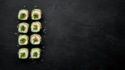 Sushi roll with avocado, cucumber and tomato. Japanese cuisine. Top view. On a black background.