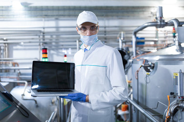 man in a white robe and a mask with a laptop in his hands is at the factory