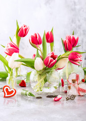 Pink and white tulips in glass vases on the light gray background. A gift for valentine's day. Greeting card for mother's day.