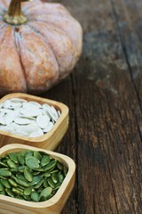 Pumpkin grain in wooden bowl and fresh pumpkin fruit on classic wooden table background, cereal